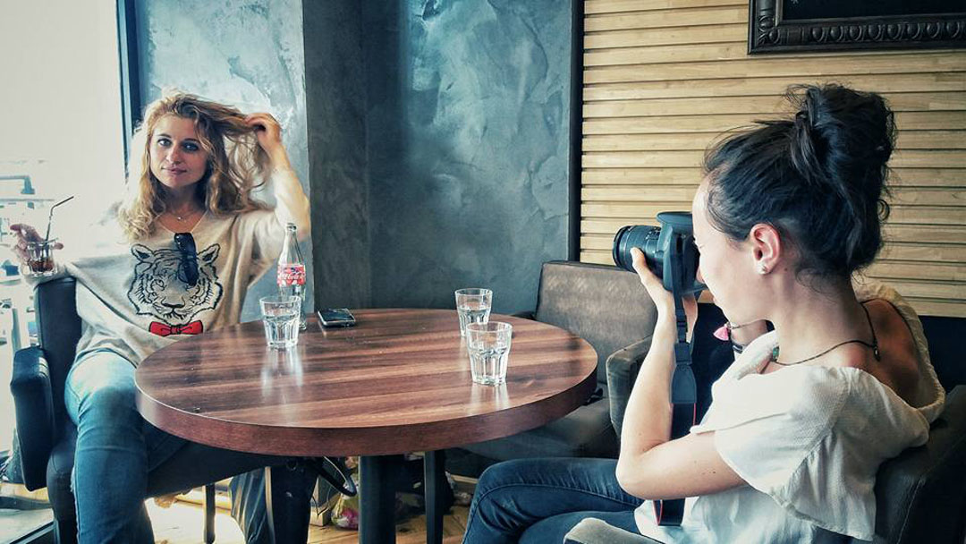 Stagiaire photo en shooting avec modèle assise au café - Elodie Frigot Photographe