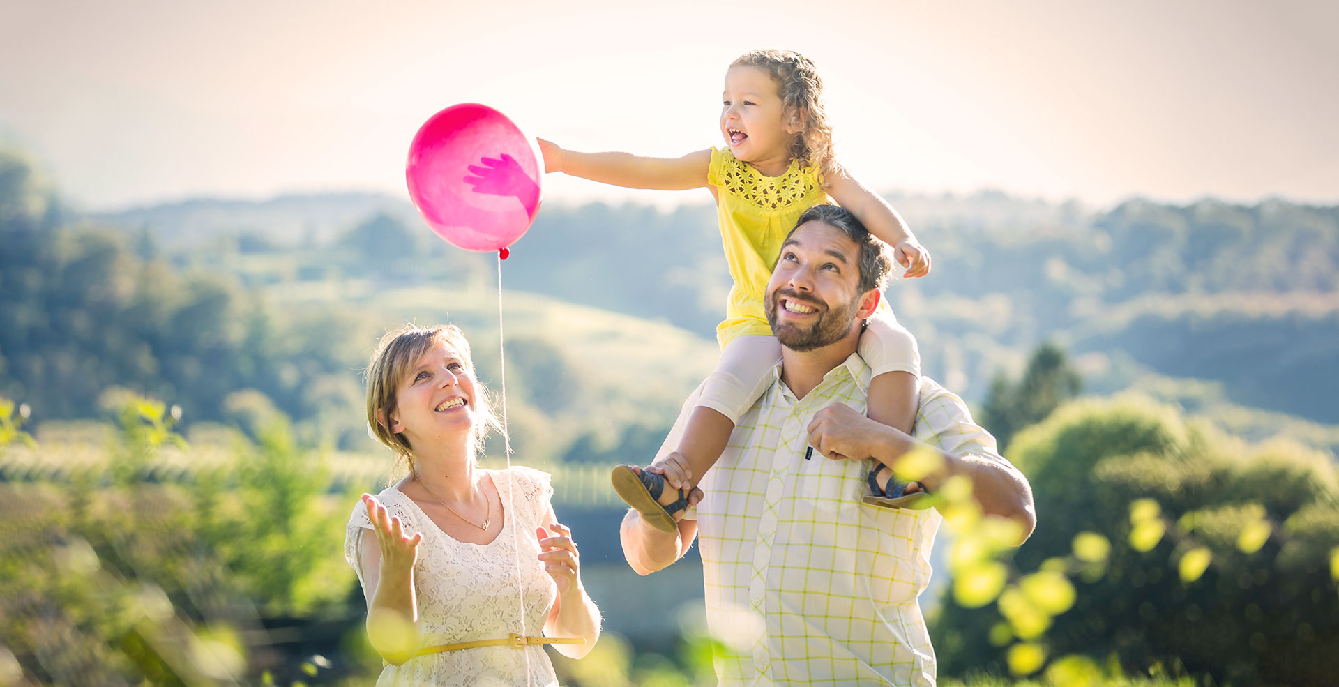 photo de famille parents enfant jouant avec un ballon dans la nature