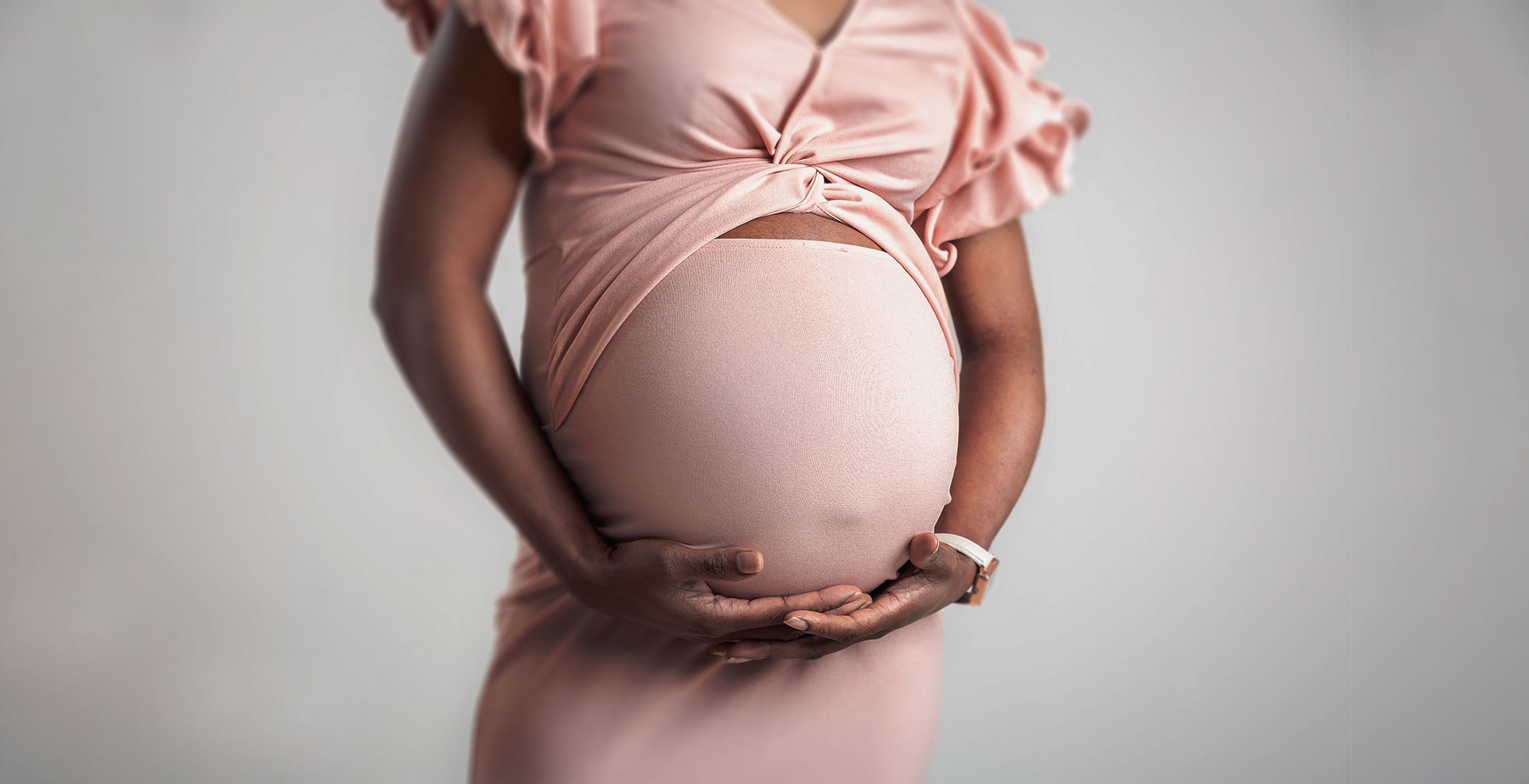 photo de grossesse en robe moulante rose au studio